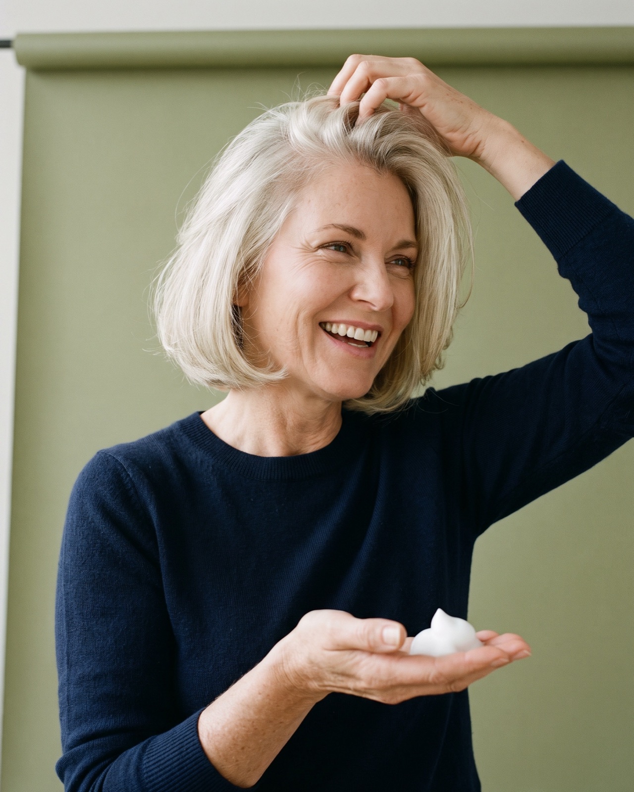 Mujer con un bob voluminoso rubio platino levantándose las raíces, con un poco de espuma en la mano