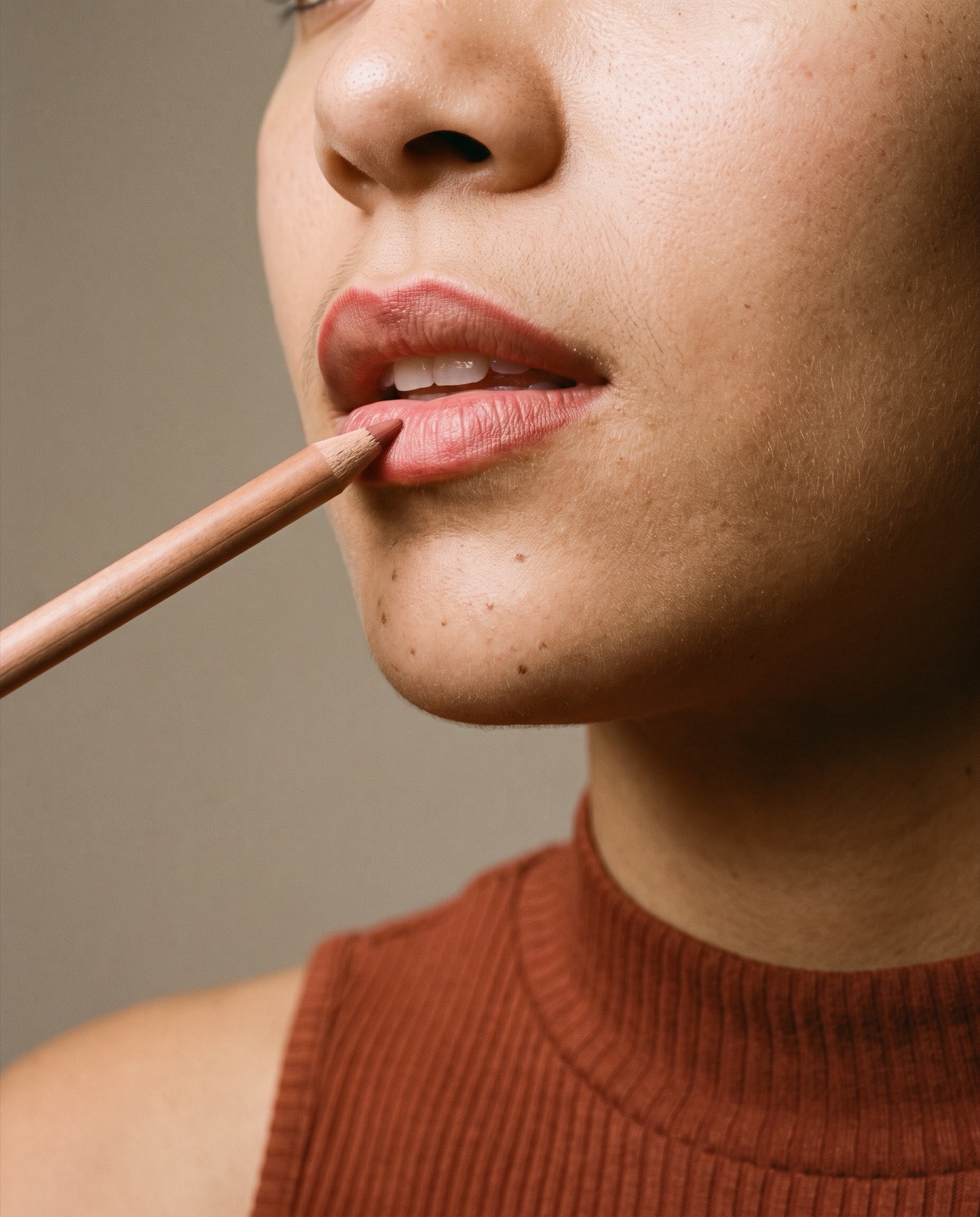 Primer plano de un perfilador color palo de rosa trazando el contorno de los labios