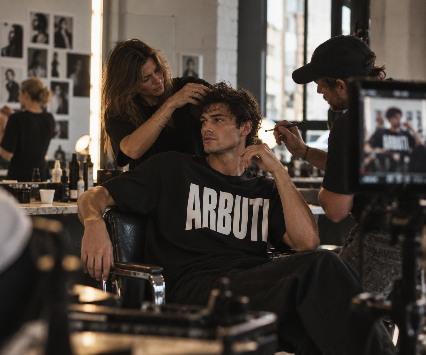 Una estilista da forma a los rizos de un hombre con camiseta de ARBUTI en el sillón de peluquería