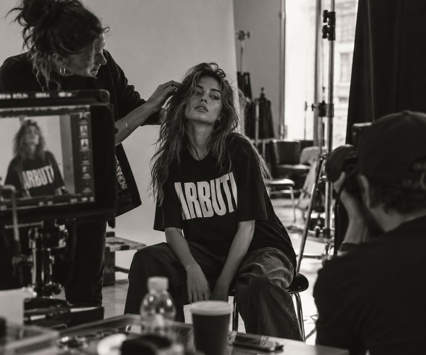 Stylistka upravuje vlasy modelce v tričku ARBUTI na place, v popředí kamera a monitor